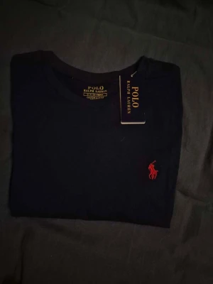Svart t-shirt från Polo Ralph Lauren - Säljer en t-shirt från Ralph lauren | I färgen mörkblå med röd logga och storlek S | Helt ny och fräsch | Hör av er för mer information/bilder! 