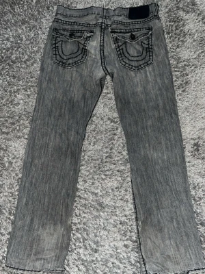 Legendary Vintage True Religion Jeans Herr - Äkta skitsällsynta Vintage Ricky true religion jeans, jätte feta o sköna, den har skönt vintage material inför sommaren. Litet slit på knät men rätt så chill ändå inget stort! Också slit längst ner på jeansen vid vikningen men de gör den bara mer swag 🤘. Annars är den i bra skick.