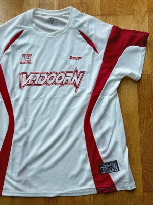 Vit och röd baskettröja Veidoorn - Säljer en sportig från Veidoorn i vitt med röda detaljer och tryck. Tröjan har rund hals, korta ärmar och är tillverkad i ett lätt och ventilerande material. Perfekt för träning eller bara om man vill vara snygg :)