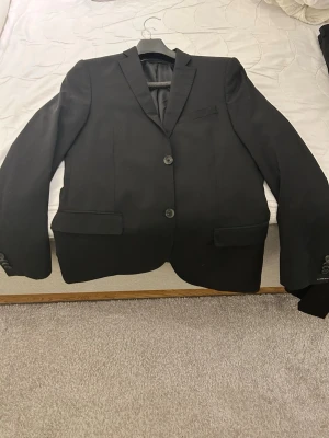 Kavaj & kostymbyxor - J.Lindeberg - Snygg svart kavaj ifrån Lindberg, kavajen har två fickor med en bröstficka även. Kostymbyxorna är svarta och går till kavajen med märke innuti av just Lindberg