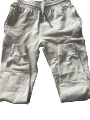 Beiga mjukisbyxor med dragsko - Säljer ett par beiga mjukisbyxor med resår i midjan och dragsko. Byxorna har ribbade muddar vid bensluten och sidofickor. Perfekta för chill dagar och riktigt sköna att ha på sig. Materialet känns mjukt och stretchigt.