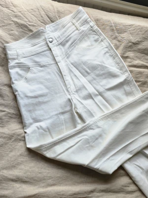 Vita highwaist jeans - Säljer ett par vita jeans med hög midja. Klassisk femficksmodell med bälteshällor och knappgylf. Jeansen är i ett mjukt denimtyg som känns skönt mot huden och passar perfekt till en avslappnad stil.