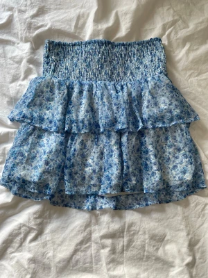 Blå blommig kjol  - Blå blommig volang kjol som även fungerar som topp, från Vero Moda i storlek s