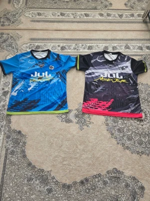 JUL kortärmade t-shirts med tryck - En sportig blå tröja med svarta och vita detaljer. Den ser energisk och lättsam ut och passar bra till vardags eller träning. Passar med: Svarta shorts Mörkblå eller svarta jeans Vita eller svarta sneakers.                             Svart NINETTA-tröjan En mörk tröja med grå, rosa och gröna detaljer. Den ser lite tuffare och modernare ut. Passar med: Svarta jeans Svarta shorts Grå mjukisbyxor Vita eller svarta sneakers 