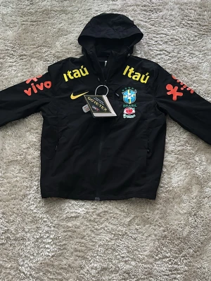 Svart Brasil Nike jacka med huva - Den sitter mer som S skulle jag nog säga(tänk på de innan köp)🙌, helt oanvänd