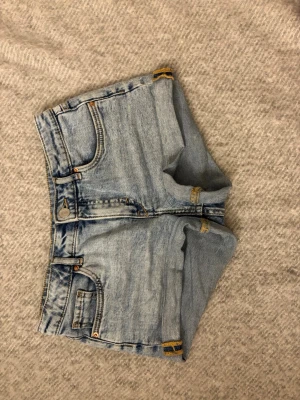 Mid-waist denimshorts med dubbel linning - Mid-waist i ljusblå denim med dubbel linning och justerbar midja. De har en stilren design med två lager och justerbar midja. Passar dig som gillar och trendiga plagg. (Ca W25, men justerbart då de är från barnavdelningen) (35 cm rakt över midjan)
