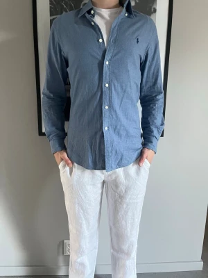 Blå skjorta från Ralph Lauren - Polo Ralph lauren skjorta! Nypris: 2399 kr, säljs för: 499 kr. Modellen är 183 lång och väger 75kg. Säljes i befintligt skick. (Skick: 9/10)  
