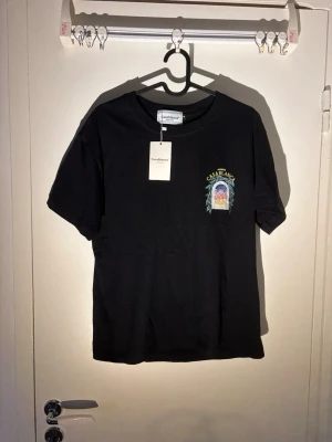 Casablanca t-shirt - Snygg svart t-shirt från Casablanca med färgglatt tryck av en byggnad och gröna blad på ryggen samt mindre tryck på bröstet. Klassisk passform och rund hals. Perfekt för dig som vill ha en unik och trendig tee med cool grafik.