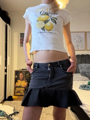 Svart jeanskjol med volang - Säljer en svart kortkjol med volangkant och jeanslook. Kjolen har klassiska jeansfickor fram och bak, samt knapp och dragkedja i midjan. Perfekt för dig som gillar en edgy och trendig stil. Jag har gjort den själv och då sytt den själv, därav att den inte är perfekt. Lite ojämn i bak och lite i fram. Skriv till mig om ni vill ha fler bilder eller om ni tänker på något!!😊🫰