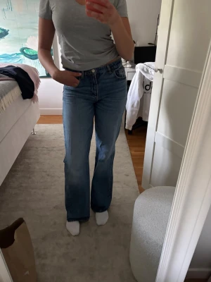 Blå vida jeans  - Säljer ett par klassiska blå jeans med vid passform och medelhög midja. Jeansen har fem fickor och stängs med dragkedja och knapp. Perfekta till vardags och lätta att styla med olika toppar.