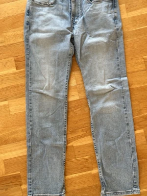 Ljusblå raka jeans från Levi's - Säljer ett par klassiska ljusblå jeans från Levi's med raka ben och femficksmodell. Jeansen har normal midja och är tillverkade i slitstark denim. Perfekta för en avslappnad och trendig look.