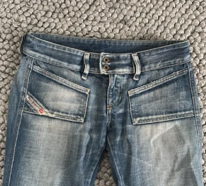 Diesel bootcut jeans - Snygga blå jeans från Diesel. Midjemåttet är 39 cm rakt över och innerbenslängden är 75 cm. Köpta här på plick men säljer då dem tyvärr inte passade.   Nypris är ca 1800kr.