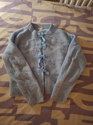 Ljusblå stickad tröja med rosett - Säljer denna ljusblåa stickade tröjan med rosetter från Gina tricot i strl 158/164cm. Använd några få gånger och är i mycket fint skick. Minns inte exakta nypris men ca 250-350kr. Kontakta mig vid funderingar. Köp gärna en bundle för att spara på frakten!