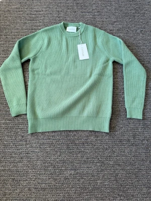 Grön stickad tröja från Ciszere - Nypris 999kr! Helt orörd. Snygg ljusgrön stickad tröja från Ciszere med rund halsringning och ribbstickad struktur. Tröjan har långa ärmar och breda muddar vid ärmslut och nederkant. Perfekt för dig som gillar stilrena och trendiga plagg.