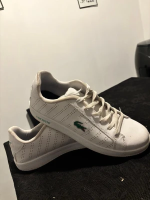 Vita Lacoste sneakers med grönt märke - Säljer schyst Lacoste skor som är sparsamt andvända och i mycket bra skick🙌 Priset kan diskuteras!