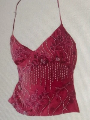 Röd paljettprydd linnetopp. - Snygg röd linnetopp med tunna axelband och v-ringning. Toppen är dekorerad med paljetter och broderade blommor som ger en extra festlig känsla. Perfekt för dig som vill sticka ut med detaljer och färg.