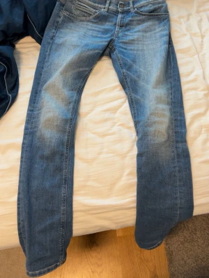 Blå skinny jeans från Dondup - Snygga blå skinny fit jeans från Dondup, modell George. Jeansen har klassisk femficksdesign, ljus tvätt med slitningar och är tillverkade i Italien. Perfekta för dig som gillar en smal passform och stilren look. Nypris 3700