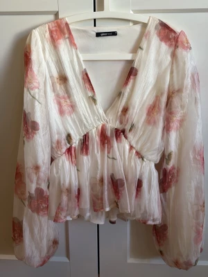 Blommig chiffongblus från Glamorous - •Säljer denna blommiga blus i tunn vit chiffon. Djup v-ringning, volang nedtill och långa puffärmar ger en luftig och trendig look.                                                                         Märke• GinaTricot                                               Köpt för• ca 400kr                                              Mitt pris• 190kr                                                     Storlek• 38