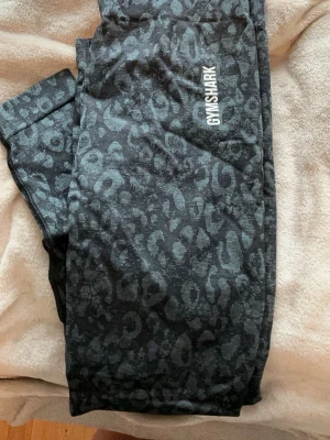 Svarta leopardmönstrade leggings Gymshark - Säljer ett par svarta leggings från Gymshark med grått leopardmönster. De har hög midja och scrunch-detalj bak. Aldrig använda. 