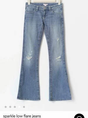 Blå sparkle low flare jeans Gina Tricot - Snygga blå low flare jeans från Gina Tricot med slitningar framtill och broderade bakfickor med glittriga detaljer. Jeansen har låg midja och utsvängda ben, perfekt för en trendig och avslappnad look. Tillverkade i mjuk denim med stretch. Avklippta där nere men Innerbenslängden är nu 74cm!