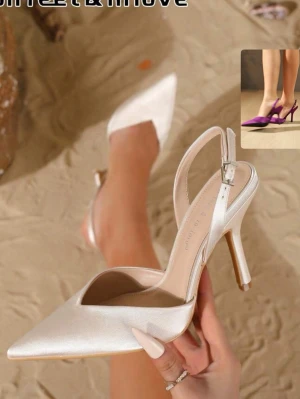 Champange klackar spetsiga - Stilrena vita pumps med spetsig tå och öppen häl. Skon har en smal rem med silverfärgat spänne runt ankeln och en elegant hög klack. Materialet ser ut att vara slätt och glansigt, vilket ger en lyxig känsla. Perfekta för att lyfta vilken outfit som helst.