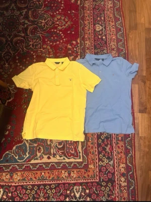 Två pikétröjor från Gant - Säljer två klassiska pikétröjor från Gant, en i ljusblått och en i gult. Båda har krage, korta ärmar och liten logga på bröstet. Perfekta för en avslappnad men snygg stil. Materialet är mjuk bomull som andas bra.