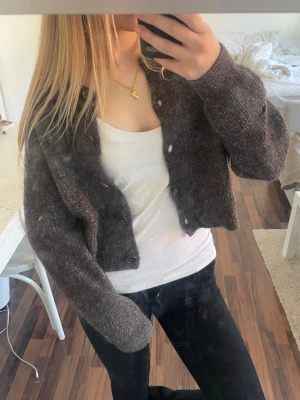 Kofta från lindex - Säljer en mörkbrun/grå stickad cropped kofta från Lindex. Den är i storlek L men är väldigt liten i storleken (mer som S/XS) Den är köpt begagnad men är i relativt bra skick förutom att den har ett hål i armen (bild 3)