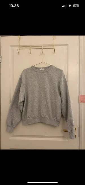 Grå basic sweatshirt - En enkel och stilren grå sweatshirt i mjukt material. Tröjan har rund halsringning, ribbade muddar vid ärmslut och nederkant samt en relaxed passform. Perfekt för en chill och avslappnad look. Märke och storlek är ej angivet.