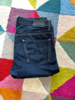 Mörkblå raka jeans från J. Lindeberg - Hej! Säljer dessa jeans från J. Lindeberg i storlek 32/32. Dessa jeans är riktigt snygga och är i straight passform. Kostar runt 1400 nya. Hör av er vid minsta fundering! Pris är ej hugget i sten!