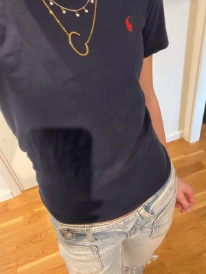 Ralph Laurent - Marinblå tröja med röd logga från POLO Ralph Laurent. Har använt ett fåtal gånger men i ganska bra skick. Ser en liten puder fläckar som borde gå bort i tvätten. Kan sänka priset men försöker tjäna så mycket som möjligt.