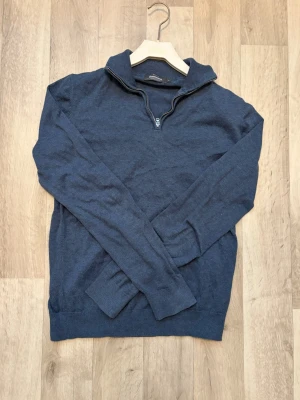 Blå halvzip tröja från Dressmann - Mörkblå stickad tröja från Dressmann i Supima bomull. Tröjan har halv dragkedja vid halsen och ribbade muddar vid ärmslut och nederkant. Perfekt för lager på lager och enkel att matcha med olika outfits. Använd fåtal gånger.