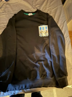 Svart sweatshirt från Casablanca - Svart sweatshirt från Casablanca med tryck av ett konstnärligt motiv och texten 'Casa Blanca' på bröstet och ryggen. Tröjan har rund halsringning och långa ärmar. Perfekt för dig som gillar streetwear och snygga prints. Pris kan diskuteras vid snabb affär 