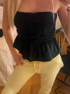 Svart axelbandslös topp med volang - Säljer en svart axelbandslös fest topp med volang nedtill❤️