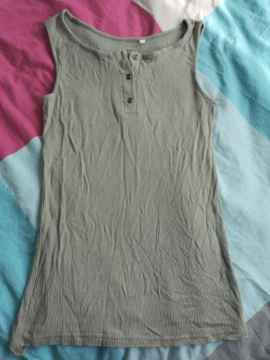 Ribbad grå linnetopp från Name It - Y2k stil längre linne ifrån name it. Perfekt till sommaren eller parat med low waist jeans och en kofta. 