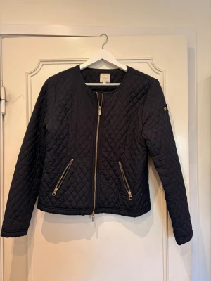 Mörkblå cardigan  - Snygg mörkblå cardiganjacka med guldiga detaljer. Jackan har rund halsringning och långa ärmar. I storlek M men tycker den sitter lite mindre än M. 