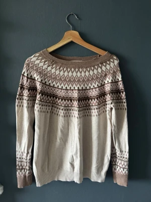 Beige och brun stickad tröja Esprit - Stickad tröja från Esprit i beige med brunt och vitt mönster över bröst, axlar och ärmar. Den har liten fläck på framsida! Tröjan har rund halsringning och ribbade muddar. Perfekt nu inför vår!💞
