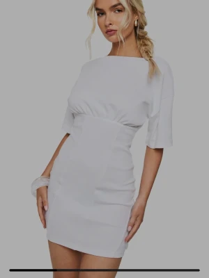 Vit kortärmad figurnära klänning - Snygg vit klänning med korta ärmar och figurnära passform. Klänningen har en markerad midja och enkel, stilren design som ger en modern look. Perfekt för dig som gillar minimalistisk stil och vill ha något som sticker ut utan att vara för mycket.