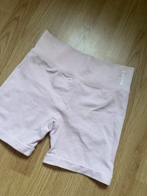 Ljusroa shorts från DFYNE - Säljer ett par ljusrosa seamless shorts från DFYNE med diskret logga framtill. Shortsen har en tight passform och är perfekta för träning eller chill. Materialet är mjukt och stretchigt syntet som formar sig efter kroppen.