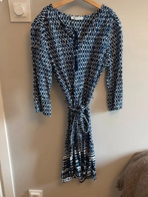 Blåvit mönstrad långklänning Lounge - Säljer en blåvit långklänning från Lounge Klänningen har trekvartsärm, v-ringning och knyt i midjan för en snygg siluett. Perfekt för sommarens alla tillfällen!