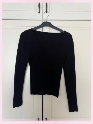 Svart ribbstickad tröja med v-ringning - 💕En svart, ribbstickad tröja med smal passform och djup v-ringning framtill. Tröjan har långa ärmar och är tillverkad i ett stretchigt material som sitter snyggt på kroppen. Perfekt att styla med jeans eller kjol.💕M-L storlek