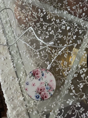 Blommig trådlös laddare Ideal of Sweden - Snygg rund trådlös laddare från Ideal of Sweden med blommigt mönster i rosa, blått och grönt. Laddaren har vit kant och medföljande vit USB-kabel. Perfekt för dig som vill ha en stilren och praktisk accessoar till mobilen.