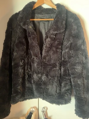 Svart pälsjacka  - Snygg svart pälsjacka från Vero Moda i storlek L. Jackan har mjukt fuskpälsmaterial, klassisk krage och knäppning framtill. Perfekt nu till våren och sommarkvällarna och ger en trendig look till din outfit!❤️