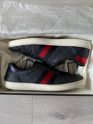 Gucci Ace Sneaker - Svarta Ace Sneakers från Gucci. Små creasingar samt liten skada på ormskinnet på hälen samt liten spricka vid creases annars helt fläckfria. Allt og tillkommer, dvs kvitto, låda, extra snören och dustbags.
