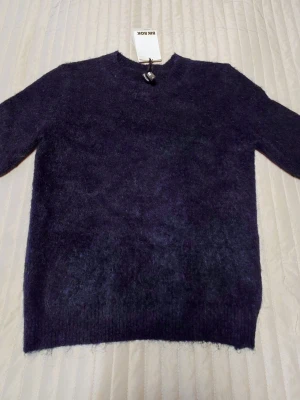 Mörklila stickad tröja från Bik Bok - Mysig stickad tröja i mörklila från Bik Bok. Tröjan har rund halsringning, kort ärm och är gjord i mohair.  Perfekt för kalla dagar när du vill vara både varm och snygg.