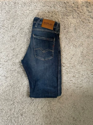 Mörkblå jeans från Replay W28 L34 - Snygga mörkblå jeans från Replay med klassisk femficksdesign och kontrastsömmar. Priset är inte spikat, Skulle säga att de passar någon som är runt 170-175 lång, Jeansen har en läderpatch med logga bak i midjan och coola detaljer på bakfickorna. Tillverkade i stretchig denim för skön passform.