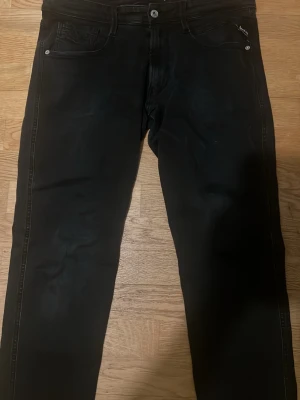 Svarta jeans från Nudie Jeans - Säljer ett par svarta jeans från Nudie Jeans med klassisk femficksmodell och raka ben. Jeansen har svarta sömmar och diskret logga på bakfickan. Tillverkade i mjuk denim som sitter snyggt och bekvämt.