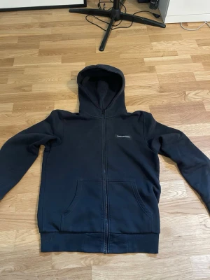 Svart zip hoodie från Peak Performance - Säljer en svart hoodie med dragkedja från Peak Performance. Hoodien har huva, två stora fickor framtill och diskret logga på bröstet. Perfekt för en chill och avslappnad stil. Materialet känns mjukt och bekvämt.