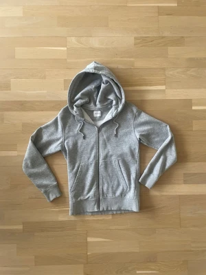 Grå zip hoodie  - En grå zip hoddie från Jack and Jones. Jätte bra skick. Ny pris ligger på 400 kr. Pris kan diskuteras vid snabb affär. 