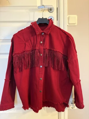 Röd overshirt med fransar - Cool röd jacka från Zara  med fransar över bröstet och ryggen. Jackan har råa kanter, tryckknappar framtill och en avslappnad passform. Materialet påminer om demin💕