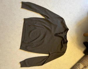  Junk de Luxe tröja - Snygg brun stickad tröja från Junk de Luxe med fyra knappar vid halsen och ribbade muddar. Tröjan har en klassisk passform och är perfekt för lager på lager. Materialet känns mjukt och bekvämt.(ordinarie pris:989kr, en liten fläck som syns på bilden också)